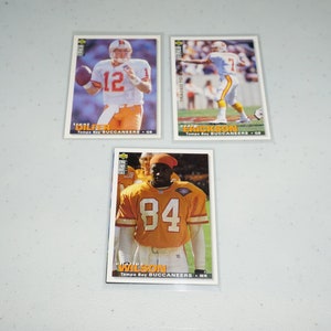 May include: Three trading cards featuring Tampa Bay Buccaneers players. The cards are white with red and blue accents. The top card features a photo of Trent Dilfer, the middle card features a photo of Brad Erickson, and the bottom card features a photo of Charles Wilson.