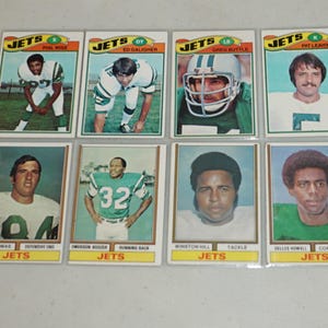 Puede incluir: Ocho tarjetas de colección de fútbol de los New York Jets. Cada tarjeta presenta un retrato de jugador, el logotipo del equipo y el nombre del jugador. Las tarjetas son rectangulares con borde blanco y texto amarillo.