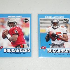 May include: Two vintage football trading cards featuring players from the Tampa Bay Buccaneers. The card on the left features Shaun King, quarterback, and the card on the right features Reidel Anthony, wide receiver.