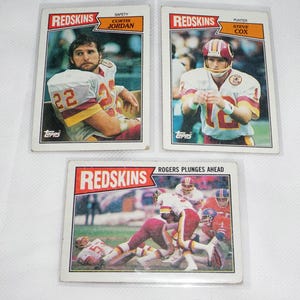 May include: Three vintage Topps trading cards featuring Washington Redskins football players. The cards feature Curtis Jordan, Steve Cox, and a game action shot of a player plunging ahead.