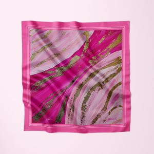 May include: A square, pink silk scarf with an abstract design. The scarf features a vibrant pink border and a central design of pink and white brushstrokes with gold accents. The artist's signature, "Alesia C," is visible in the corner.