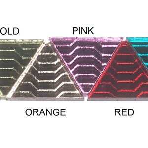 Op de afbeelding: Een rij van tien driehoekige glazen tegels in verschillende kleuren, waaronder rook, goud, roze, teal, paars, zilver, oranje, rood en blauw.