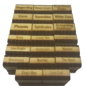 May include: A stack of wooden boxes with different names engraved on them, including Dragon King, Flower Knight, Dung Beetle Knight, Gorm, Sunstalker, White Lion, Phoenix, Spidicules, Screaming Antelope, Tyrant, Lonely Tree, Gold Smoke Knight, Lion Knight, Manhunter, Watcher, Slenderman, Butcher, The Hand, King's Man, and Lion God.