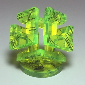 May include: A green, translucent, geometric sculpture with a complex, interwoven design. The sculpture is made of multiple pieces that are connected to form a three-dimensional shape.