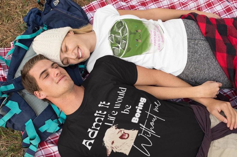 May include: A couple wearing matching t-shirts with funny sayings. The man's shirt says "Admit it Life would be Boring Without me" and features a llama. The woman's shirt says "Matcha First So I Can Slay The Shirt".