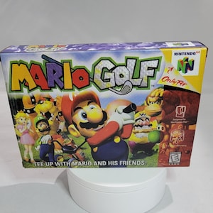May include: A purple, blue, and green Nintendo 64 game cartridge box for Mario Golf. The box features a colorful illustration of Mario swinging a golf club with other characters from the game, including Luigi, Peach, and Donkey Kong. The text "Mario Golf" is printed in large, bold letters on the front of the box. The text "Only For N" is printed in red on a white background. The text "Tee Up With Mario And His Friends!" is printed in white on a red background.