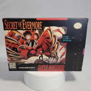 May include: A Super Nintendo Entertainment System game cartridge for Secret of Evermore, a 24 meg action adventure game. The box art features a red monster with sharp claws and a human character standing in front of it.