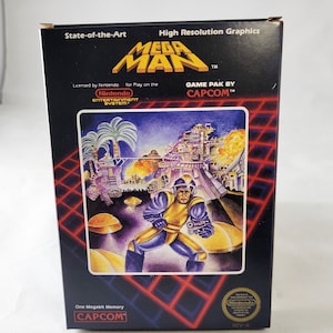 May include: A black box for the video game Mega Man, with a futuristic illustration of a character in yellow and blue armour. The box has the text "State-of-the-Art" and "High Resolution Graphics". The Nintendo and Capcom logos are also visible.