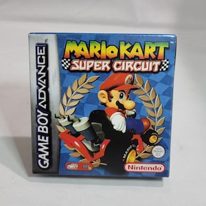 May include: A Game Boy Advance video game cartridge box for Mario Kart: Super Circuit. The box features Mario in a red kart, a blue background with laurel wreaths, and the Nintendo logo. The game title is prominently displayed.