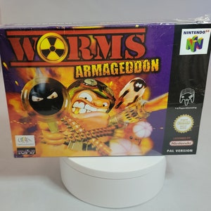 May include: A Nintendo 64 game cartridge case for Worms Armageddon. The case is purple with a yellow and black image of a worm holding a bazooka. The text "Worms Armageddon" is in white letters on a black background. The Nintendo 64 logo is in the upper right corner.