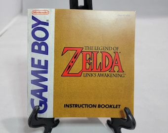 May include: The Legend of Zelda: Link's Awakening instruction booklet for the Game Boy. The booklet has a tan cover with the game's title in red and the Nintendo logo. The Game Boy logo is on the left side.