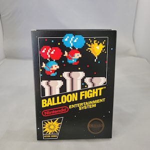 May include: A black box featuring pixelated artwork from the Nintendo game "Balloon Fight." The image shows characters with balloons, a yellow burst, and the game's title. The Nintendo logo and "Action Series" are also visible.