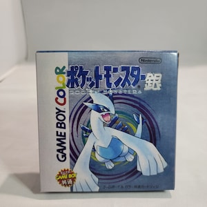 May include: A blue Game Boy Color game cartridge box with a white and blue Pokemon character on the front. The box has Japanese text that reads "Pocket Monsters" and "Nintendo".