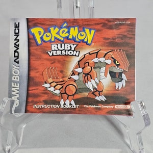 May include: A red and orange Pokemon Ruby Version instruction booklet for the Game Boy Advance. The cover features a red and orange Pokemon with sharp claws and teeth. The text on the cover reads "Pokemon Ruby Version" and "Game Boy Advance".
