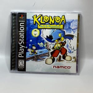 May include: A PlayStation game case for "Klonoa: Door to Phantomile." The cover art shows a cartoon character in a blue hat and red trousers, with the game's title in yellow and blue. The case is in a clear plastic case.