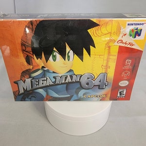 May include: A yellow, orange, and blue Nintendo 64 game cartridge case with a cartoon image of Mega Man 64 on the front. The text "Mega Man 64" is in large, white letters. The text "CAPCOM" is in smaller, white letters below the main title. The Nintendo 64 logo is in the upper right corner of the case.