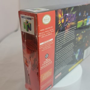 Pu&ograve; includere: Scatola sigillata del videogioco per Nintendo 64 di The Legend of Zelda: Majora's Mask. La scatola &egrave; rossa e nera con dettagli del gioco e un logo Nintendo 64. Il titolo del gioco &egrave; in un font stilizzato con una combinazione di colori oro e viola.