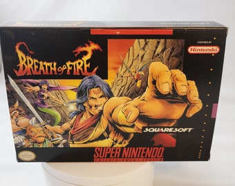 Puede incluir: Un cartucho de juego Super Nintendo Entertainment System para Breath of Fire, con una ilustración colorida de un personaje con un dragón en la parte delantera. El juego está licenciado por Nintendo y publicado por SquareSoft.