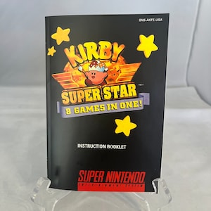 May include: A black and yellow instruction booklet for the Super Nintendo game Kirby Super Star. The cover features Kirby, a pink character with a crown, standing on a star. The text on the cover reads "Kirby Super Star" and "8 Games in One!"