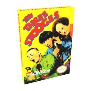 May include: A yellow box featuring a picture of the Three Stooges on the front. The box is for a Nintendo Entertainment System game called "The Three Stooges" by Activision.
