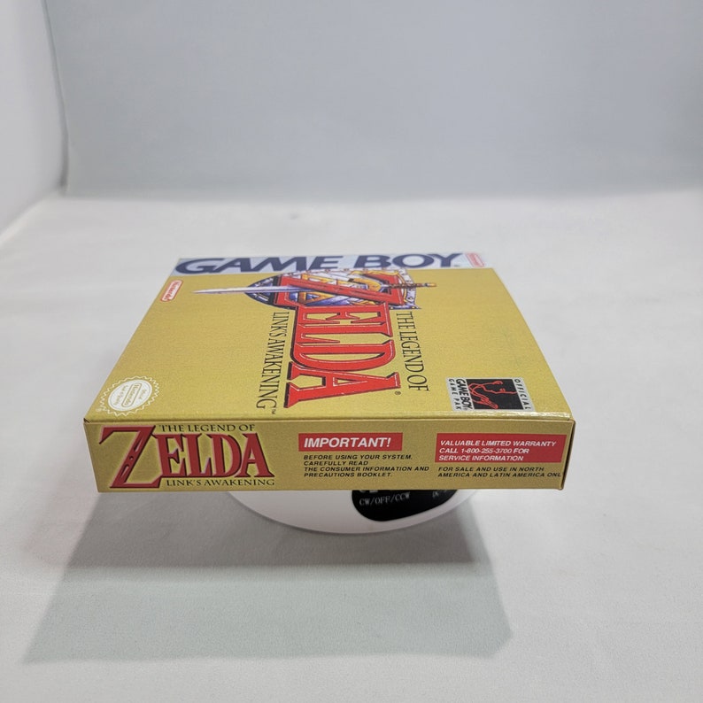 May include: A gold Game Boy cartridge case for The Legend of Zelda: Link's Awakening. The case has a picture of Link on the front with the game title and logo. The back of the case has important information about the game and warranty.
