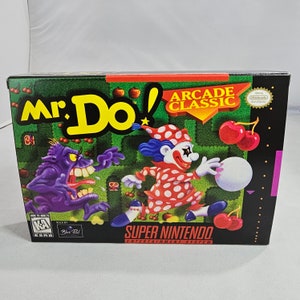 May include: A Super Nintendo Entertainment System game cartridge box for Mr. Do! Arcade Classic. The box features a colorful illustration of the game's main character, a clown with a red and white polka dot outfit, running through a maze with cherries. The box also features a purple monster with sharp teeth.