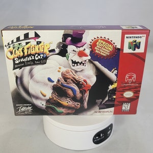 May include: A Nintendo 64 game cartridge box for ClayFighter: Sculptor's Cut. The box features a white and brown clay figure with a purple hat and a red nose. The text on the box reads "ClayFighter: Sculptor's Cut" and "Special Edition! More Gameplay! More Characters! More Humor!"