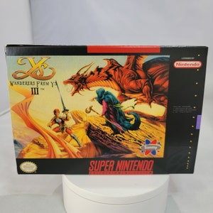 May include: Super Nintendo Entertainment System game cartridge box for Ys III: Wanderers From Ys. The box features a red dragon, a wizard, and a warrior on a desert landscape. The game is licensed by Nintendo.