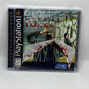May include: A PlayStation game case for "Clock Tower." The cover art features a person holding a large, bloody object with a cliffside background. The game case is in a clear plastic case with the PlayStation logo.