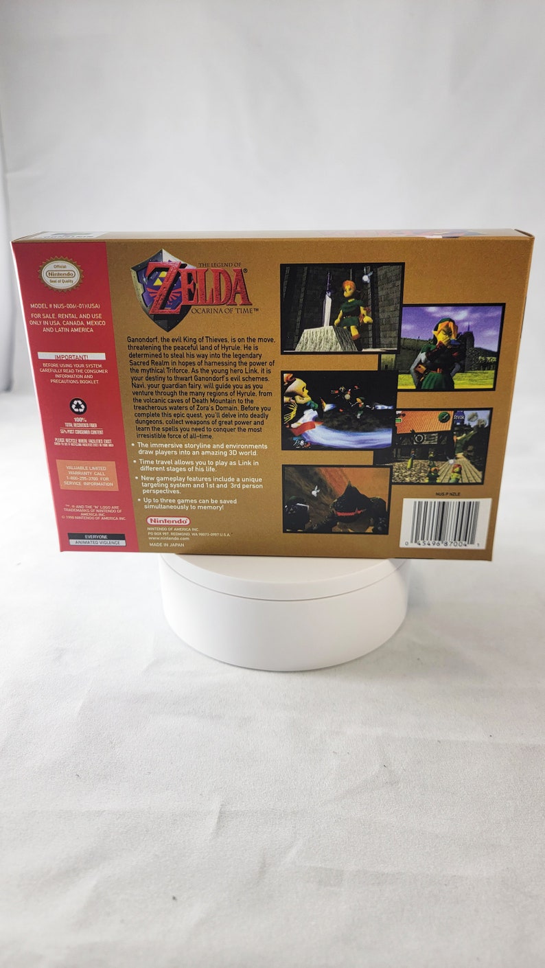 May include: A Nintendo 64 game cartridge for The Legend of Zelda: Ocarina of Time. The back of the box features a gold background with images of Link, Ganondorf, and the Triforce. The text on the box reads "Ganondorf, the evil King of Thieves, is on the move, threatening the peaceful land of Hyrule. He is determined to steal his way into the legendary Sacred Realm in hopes of harnessing the power of the mythical Triforce. As the young hero Link, it is your destiny to thwart Ganondorf's evil schemes. Navi, your guardian fairy, will guide you as you venture through the many regions of Hyrule, from the volcanic caves of Death Mountain to the treacherous waters of Zora's Domain. Before you complete this epic quest, you'll delve into deadly dungeons, collect weapons of great power and learn the spells you need to conquer the most irresistible force of all-time."