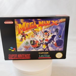 May include: A Super Nintendo Entertainment System game cartridge for Mega Man X3, licensed by Nintendo and published by Capcom. The box art features a blue and red robot character with a yellow helmet and a large gun, surrounded by other robots and a blue and white background.