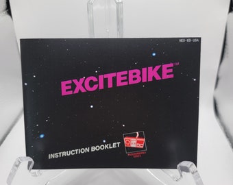 May include: Instruction booklet for the video game Excitebike. The cover is black with the game title in pink and white stars. The bottom of the booklet has the text "Instruction Booklet" and a logo for the "Programmable Series".