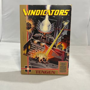 May include: A vintage game cartridge for the Nintendo Entertainment System (NES) called "Vindicators" by Tengen. The box art features a futuristic tank firing a laser beam at an enemy.
