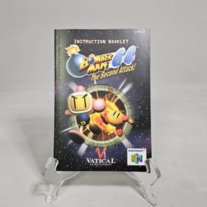 May include: A black and white instruction booklet for the Nintendo 64 game "Bomberman 64: The Second Attack!" The cover features a cartoon bomb character with a red fuse and a white face. The game is published by Vatical Entertainment.