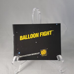 May include: Black and yellow instruction booklet for the game "Balloon Fight" with a starburst logo that says "Action Series".