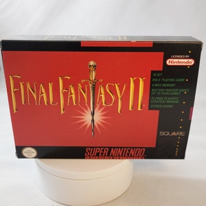 May include: A red and black Super Nintendo game cartridge box for Final Fantasy II. The box features a gold sword and the game title in gold lettering. The box also includes information about the game, such as the number of bits, memory, and save features.