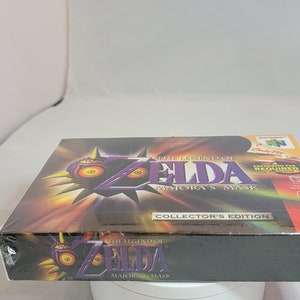 Pu&ograve; includere: Edizione da collezione sigillata di The Legend of Zelda: Majora's Mask per Nintendo 64. La scatola presenta il logo del gioco con un design a maschera viola e gialla. La scatola &egrave; avvolta in plastica trasparente.