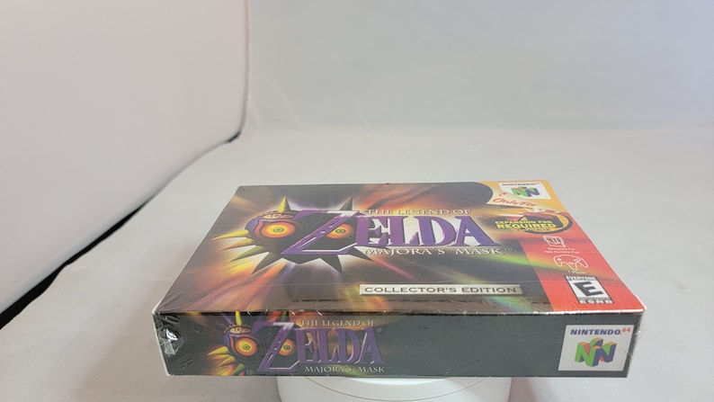 Pu&ograve; includere: Edizione da collezione sigillata di The Legend of Zelda: Majora's Mask per Nintendo 64. La scatola presenta il logo del gioco con un design a maschera viola e gialla. La scatola &egrave; avvolta in plastica trasparente.