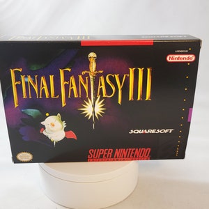 May include: A black Super Nintendo game cartridge box with a purple and red border. The box features a white and red image of a character from the game Final Fantasy III. The text "Final Fantasy III" is in gold letters on a black background. The text "Super Nintendo Entertainment System" is in red letters on a black background. The text "Licensed by Nintendo" is in white letters on a red background. The text "Squaresoft" is in white letters on a red background.