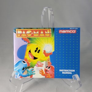 May include: A blue and yellow instruction manual for the Pac-Man video game for the Nintendo Entertainment System. The cover features a cartoon Pac-Man character with a yellow body and a blue ghost.