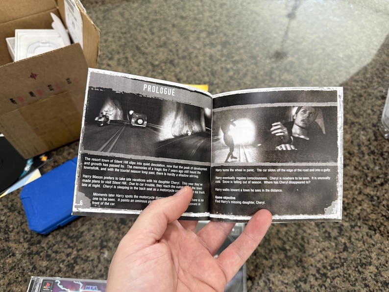 May include: Open book with black and white images and text. The title "PROLOGUE" is at the top. The images depict scenes from a video game. The text describes the story and characters. The book is held by a person.