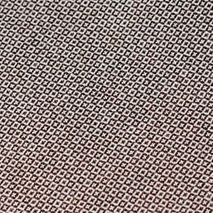 May include: A close-up of a textured fabric with a repeating pattern of small, dark squares on a light background.