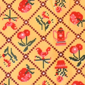 May include: A yellow fabric with a repeating pattern of red cherries, red flowers, red teapots, and red roosters. The pattern is set against a yellow background with a brown diamond grid.