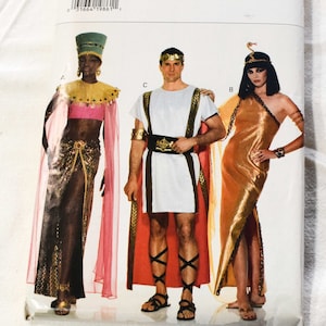 Peut inclure: Un patron de couture pour trois costumes : une robe de reine égyptienne dorée et noire, une tunique romaine blanche et une robe de déesse égyptienne dorée. Le numéro du patron est 3587.
