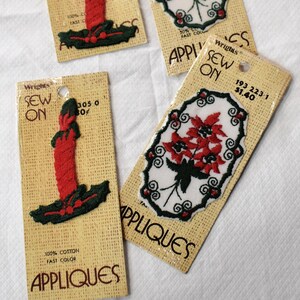 Può includere: Quattro applicazioni da cucire Wrights su supporto di cartone. Due presentano una candela rossa con foglie di agrifoglio verdi, e due presentano un motivo floreale di stella di Natale rossa entro un bordo ovale nero e bianco. Testo Sew On Appliques.