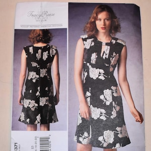 Puede incluir: Patrón de vestido Vogue Patterns American Designer Tracy Reese. El patrón presenta un vestido negro con un estampado floral de rosas blancas. El vestido tiene un escote de ojo de cerradura y una falda acampanada. La talla del patrón es E5 (14-16-18-20-22).