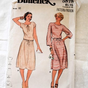Op de afbeelding: Vintage naaipatroon voor een jurk, Butterick patroonnummer 5878, maat 10. Het patroon toont twee vrouwen die jurken dragen, een in een effen kleur en een in een gestreept patroon. Het patroon is geschikt voor middelzware stretchbreistoffen.