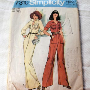 Op de afbeelding: Vintage Simplicity naaipatroon 7310. De patroonhoes toont illustraties van twee vrouwen in jumpsuits. Eén jumpsuit is crèmekleurig, de andere is roestkleurig. De envelop heeft de tekst "Simplicity" en "7310".