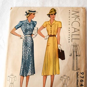 Pode incluir: Um envelope de molde impresso McCall vintage para um vestido de senhora e menina, tamanho 38. A ilustração apresenta duas variações de vestido: uma em azul com padrão branco e outra em amarelo sólido, ambas com mangas curtas e cintos.