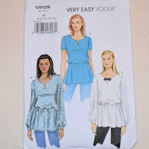 Puede incluir: Un patrón de costura titulado "V9129" de Very Easy Vogue. El patrón presenta ilustraciones de tres tops tipo túnica diferentes con diferentes largos de manga y detalles. Los tops son en azul y blanco, con un detalle de lazo en blanco y negro.